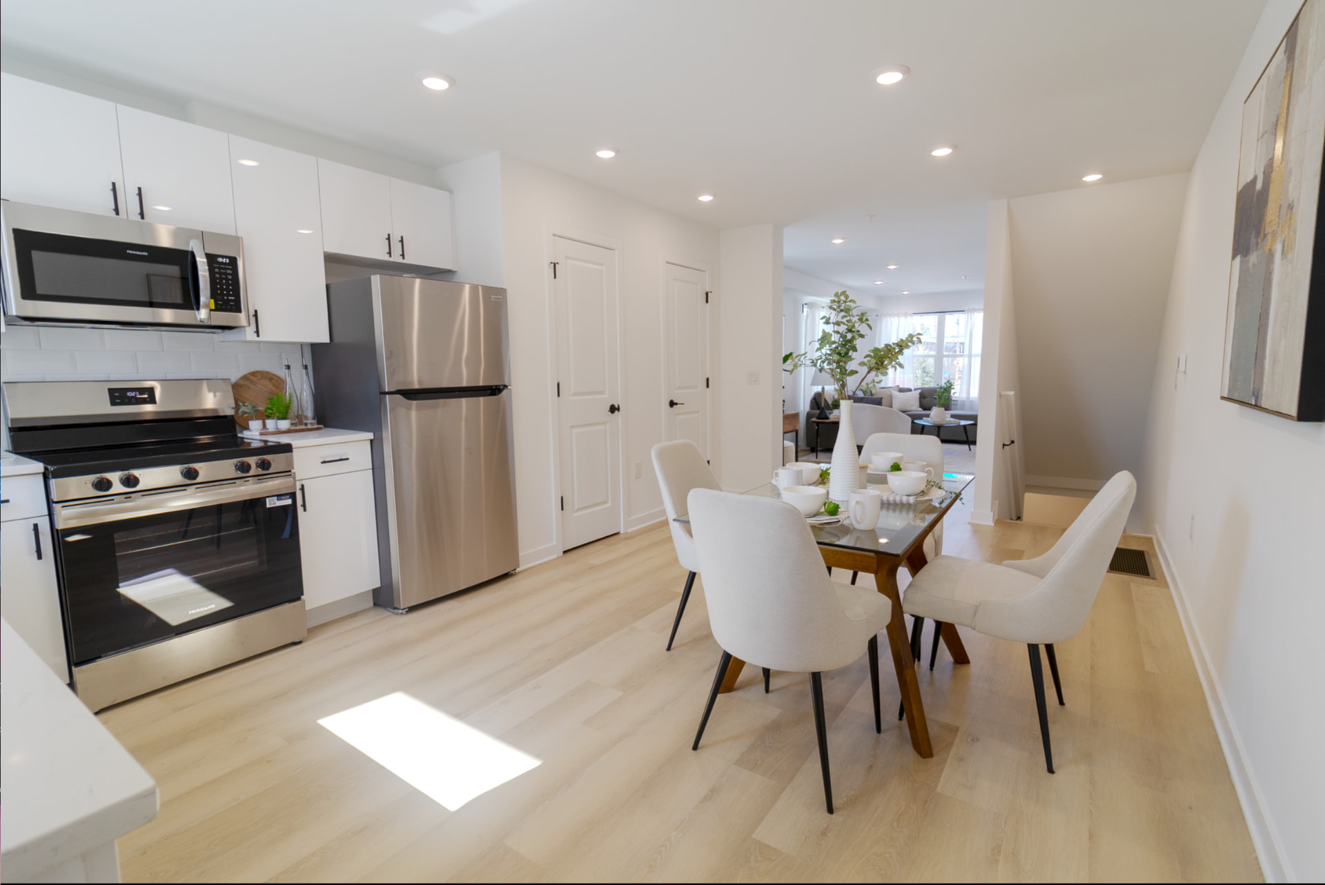 Bright white kitchen with stainless appliances opening to a dining area